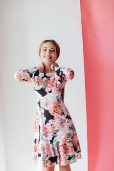 a woman in beautiful floral dress stands on a white pink background