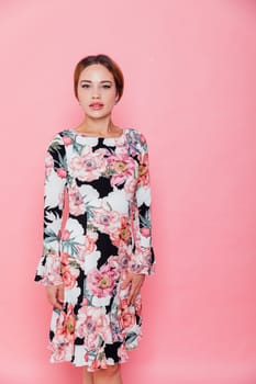 woman in a beautiful floral dress stands on a pink background