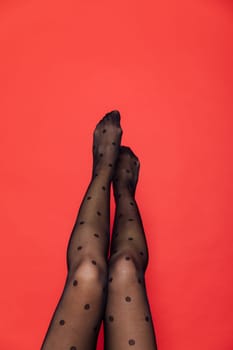 women's slender legs in black tights on red background