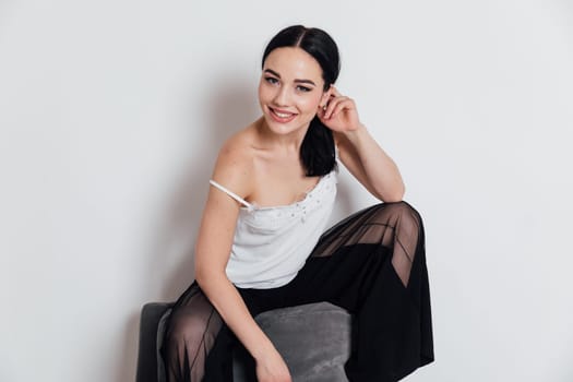 fashionable woman in black pants sits on a chair