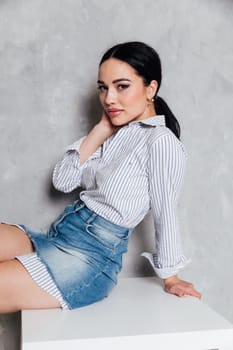 a woman in denim skirt sits on a table in a room