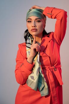 a woman in an orange dress and a headscarf standing in the room