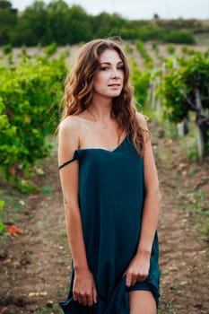 woman in a blue dress stands in vineyards