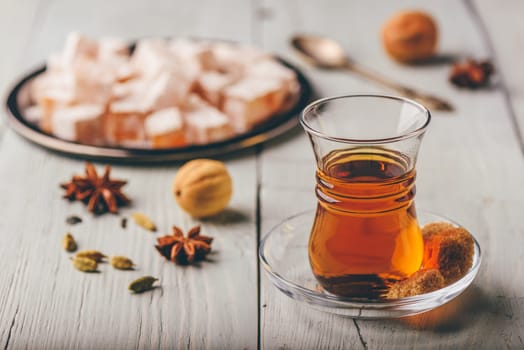 Asian tea in armudu glass with Rahat Lokum and different spices over wooden surface