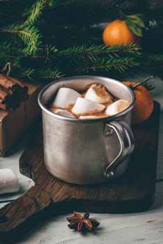 Rustic mug of hot chocolate with marshmallows on cutting board