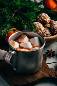 Metal mug of hot chocolate with marshmallows and gingerbread