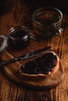 Toast with berry jam on cutting board and cup of green tea in rustic setting