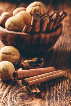 Cinnamon sticks and dried limes in wooden bowl on rustic table