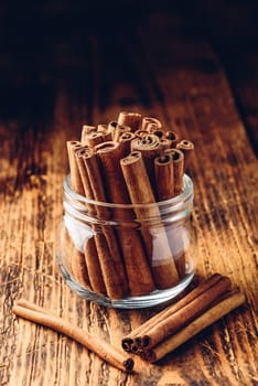 Cinnamon sticks in a glass jar over rustic wooden surface