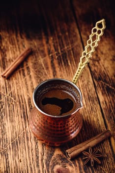 Turkish coffee with cinnamon and anise. Brewed coffee in copper cezve on wooden surface