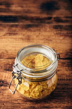 Jar full of corn flakes on a wooden surface