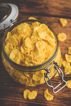 Corn flakes in a glass jar on wooden surface