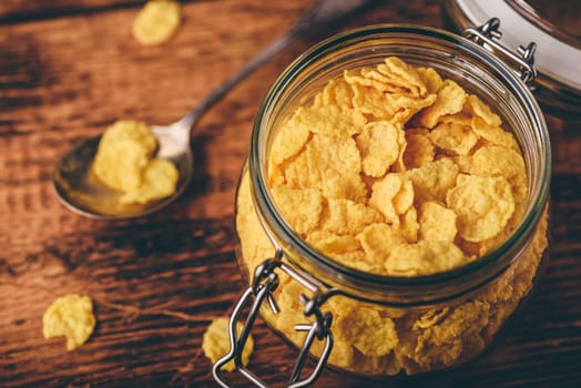 Jar of corn flakes for breakfast on wooden surface