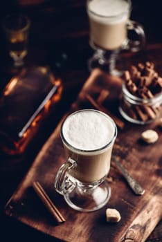 Irish coffee with cinnamon on wooden surface