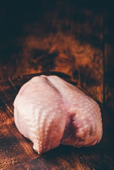 Raw chicken breast on rustic chopping board