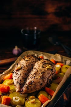 Seasoned chicken breast baked in oven with vegetables on baking sheet
