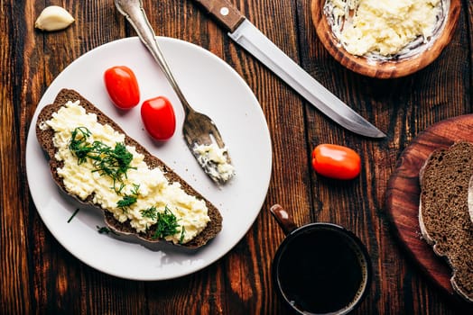 Rye bread toast with processed cheese and garlic on white plate. View from above