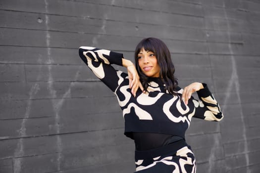 Hispanic female beauty adult confident artist dancing in the city on a grey wall background