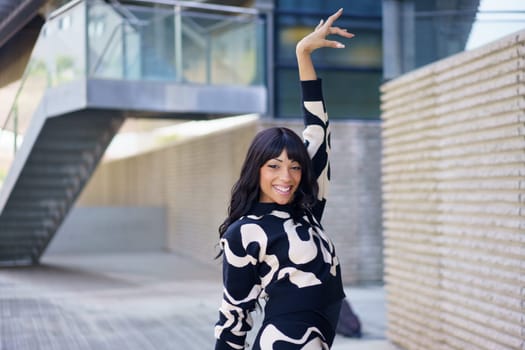 Happy elegant beauty hispanic dancer posing outside an urban building