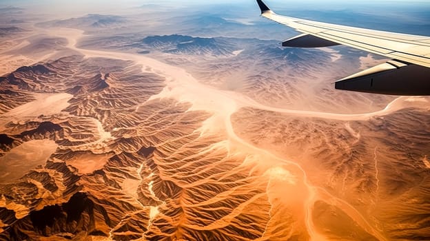 A plane is flying over a desert with mountains in the background. The sky is clear and the sun is shining brightly. The view from the plane is breathtaking and serene