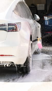 Efficiently cleaning an electric car in the comfort of a suburban driveway, combining eco-consciousness with practicality.