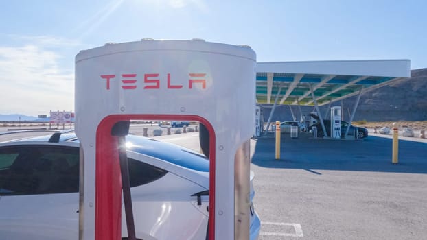 Baker, California, USA-December 3, 2022-During the day, a Tesla vehicle is seen charging at a Tesla Supercharging station, utilizing the high-speed charging infrastructure for convenient and efficient electric vehicle refueling.