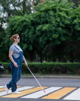 Blind pregnant woman crosses the road at a crosswalk with a cane