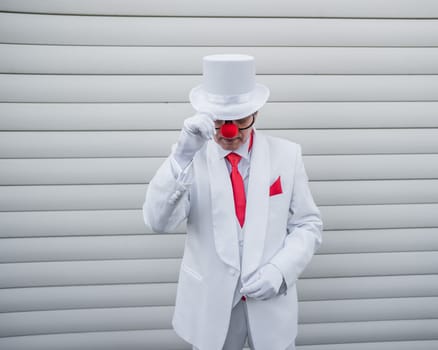 Portrait of a clown in a white classic suit and a vintage high hat