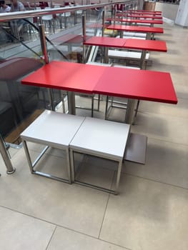 Red tables are empty in the cafe