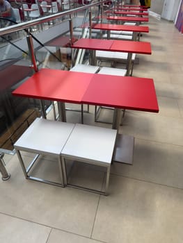 Red tables are empty in the cafe