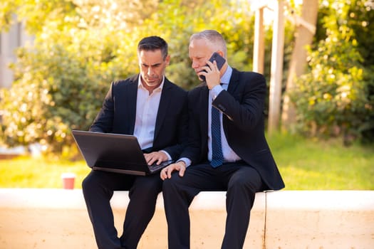 Two trusted business colleagues dressed in formal attire with a computer in hand observing the results of the work done