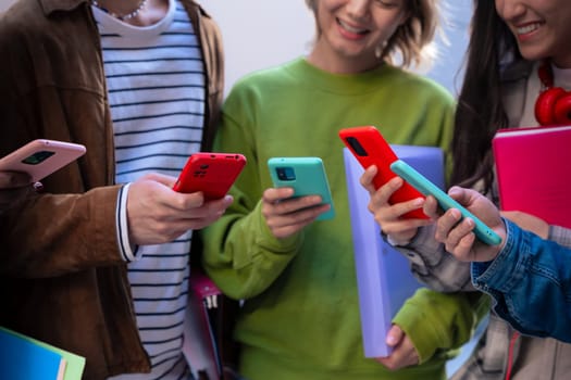 Group of friends using looking at their smartphones Multiracial teenagers browsing the internet with mobile phone on campus