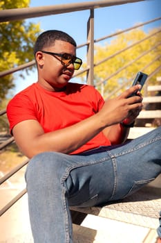 Happy Latin man smiling while browsing the internet with a telephone feeling of happiness looking at camera outdoors.