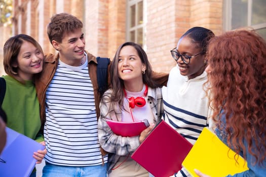 Multiracial group of students walking around college campus laughing outdoors Young community of people having fun together.