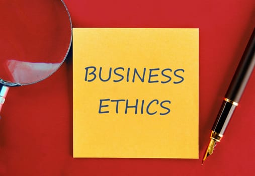 Business ethics and compliance concept. BUSINESS ETHICS on a yellow sticker on a red background