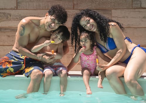 Cheerful dominican family of four enjoying summer holidays in a pool.