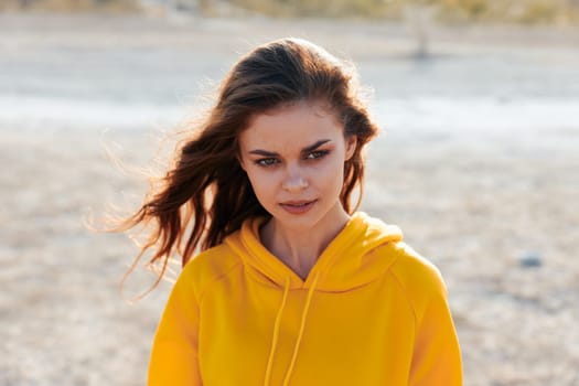 Lonely woman in yellow hoodie standing in vast desert landscape under clear blue sky