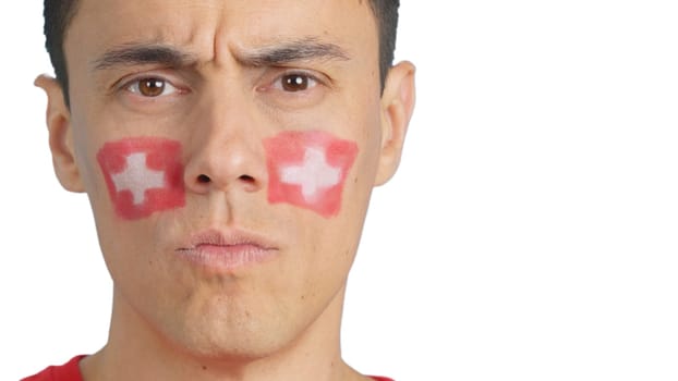 Close up of a serious man with a swiss flag painted on the face looking at camera