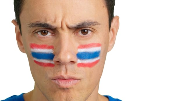 Close up of a serious man with a thai flag painted on the face looking at camera