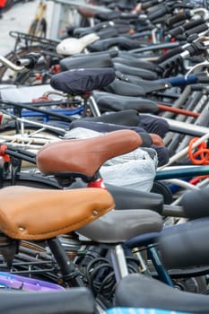 Netherlands. Bicycle parking in Amsterdam. New and old bicycles. Many bicycle saddles in vertical shot
