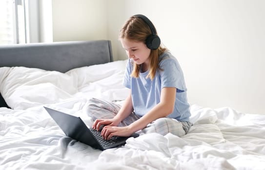 Sweet Young Girl Talking To Her Friends On Social Media Using Her Laptop While Sitting On Her Bed