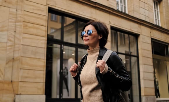 Attractive Woman In Sunglasses Walks In City With Backpack, Female Tourist Looking Around