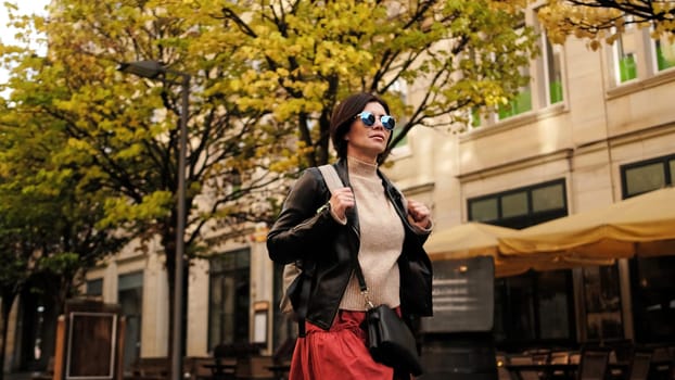 Attractive Woman In Sunglasses Walks In City With Backpack, Female Tourist Looking Around