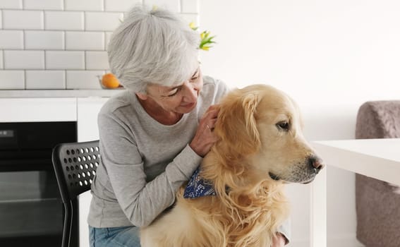 Cheerful Old Lady Petting Her Cute Golden Retriever Dog With A Smile