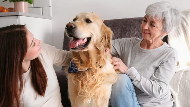 Old Woman And Her Granddaughter Having Fun With A Cute Golden Retriever Dog