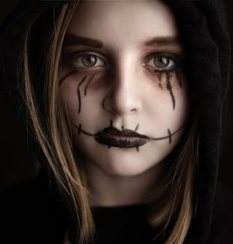 Little girl with spooky Halloween makeup looking at camera closeup portrait. Creepy child's portrait.