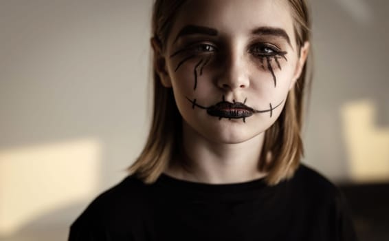 Little girl with spooky Halloween makeup brushed eyes looking at camera. Creepy kid's portrait with crazy joker expression.