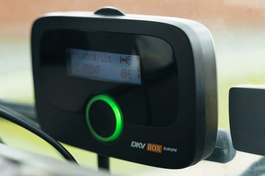 Wittenburg, Germany - May 19, 2023: A detailed view of an on-board DKV Box Europe device mounted in a vehicle, showing its digital display and illuminated green indicator.