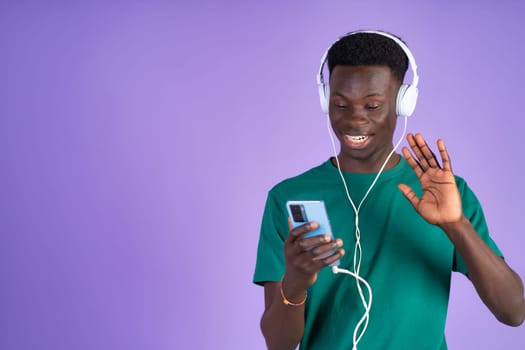 A man wearing headphones listening to music while holding a cell phone.