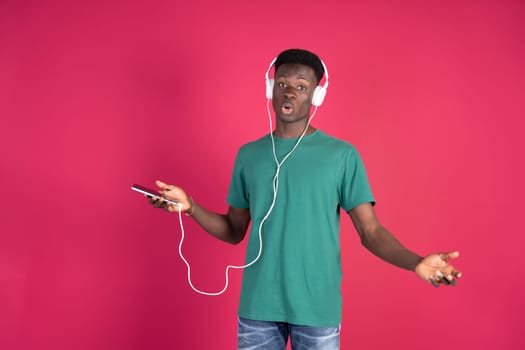 A man wearing headphones is seen holding a cell phone in his hand, appearing focused on the devices screen.